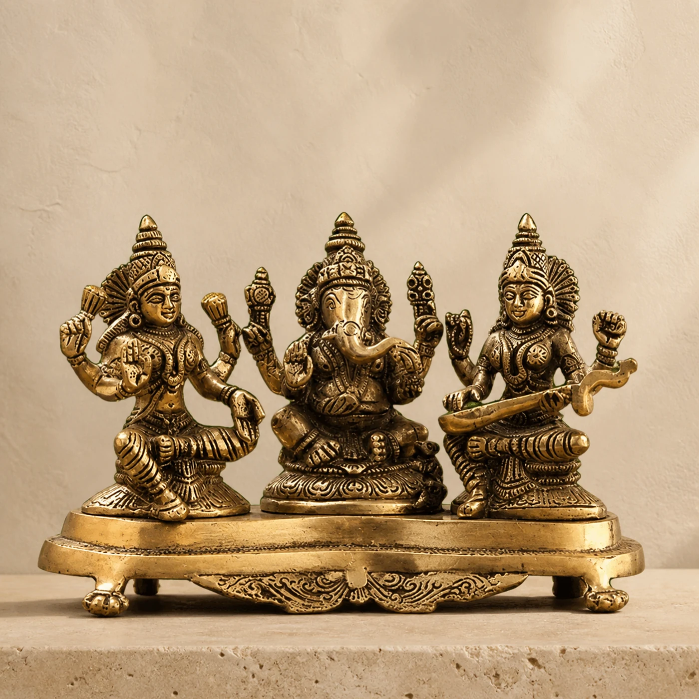 Ganesha Lakshmi Saraswati Set, a brass idols, shown on a warm neutral surface